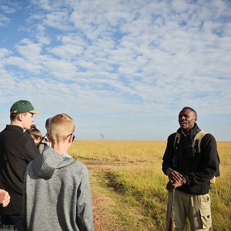 Maasai-guide i samtale med en lille gruppe besøgende på den åbne savanne